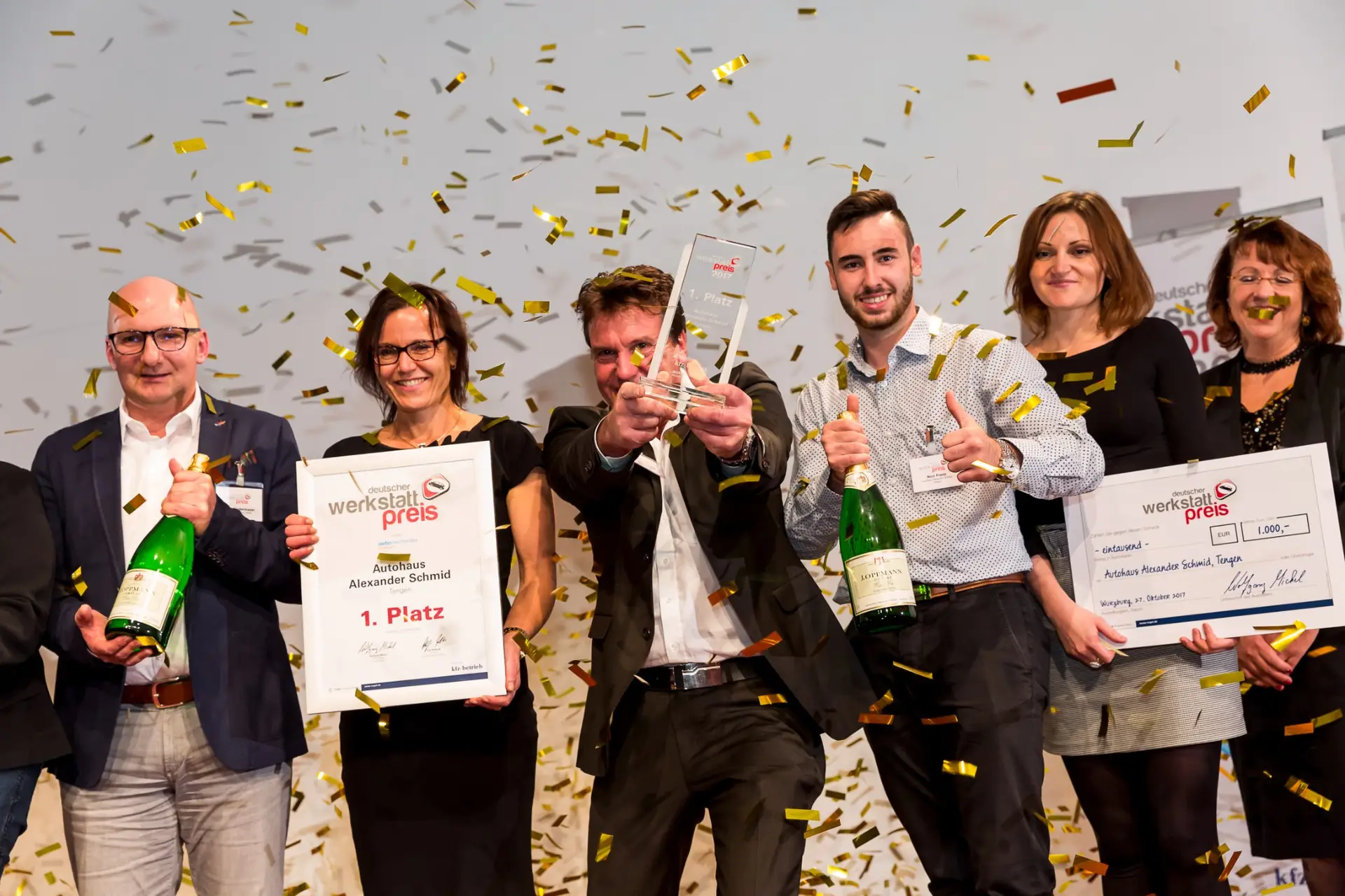 Das Team vom Autohaus Schmid jubelt mit Pokal und Urkunde über den 1. Platz beim Deutschen Werkstattpreis, dazu goldenes Konfetti