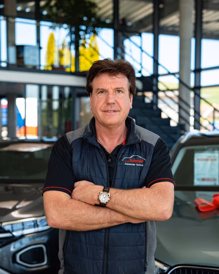 Porträt von Alexander Schmid, Geschäftsinhaber im Autohaus Schmid in Tengen, mit verschränkten Armen im Ausstellungsraum